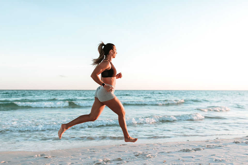 Running woman on the beach during Gym and Outdoor Fitness Photography Session Tips and Ideas by Navarre Florida Fitness photographer, Adina Preston.