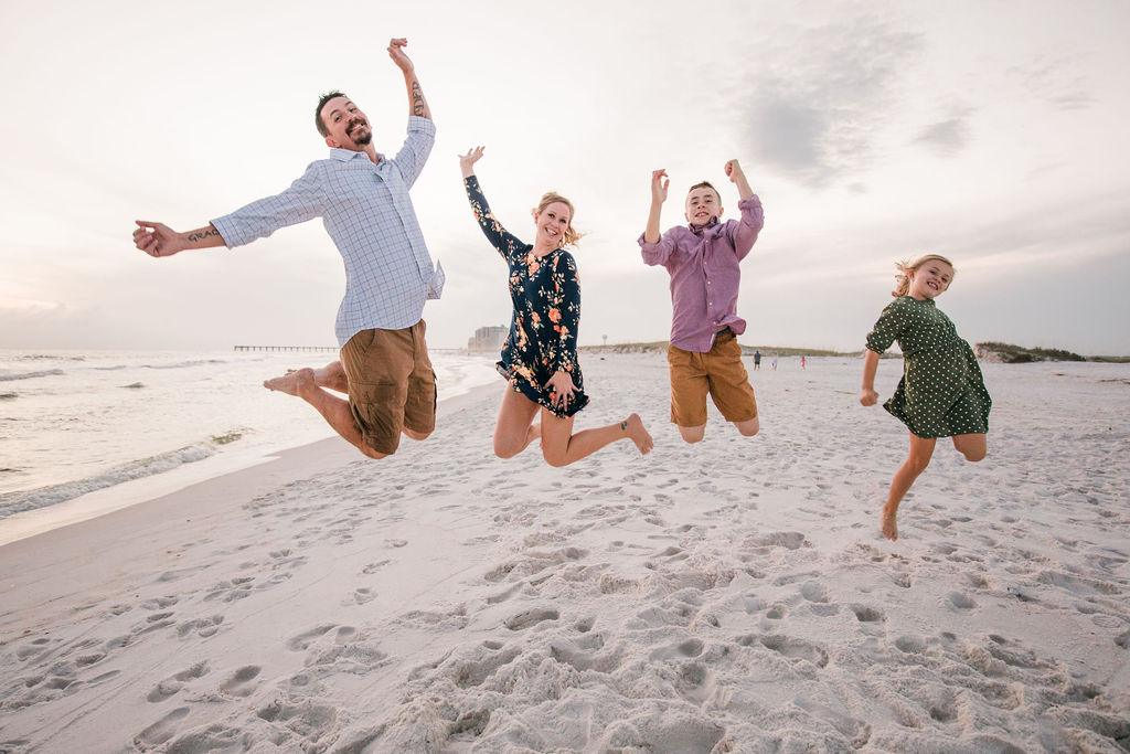 Family fun jumps during a sunset beach photo session in Navarre Beach