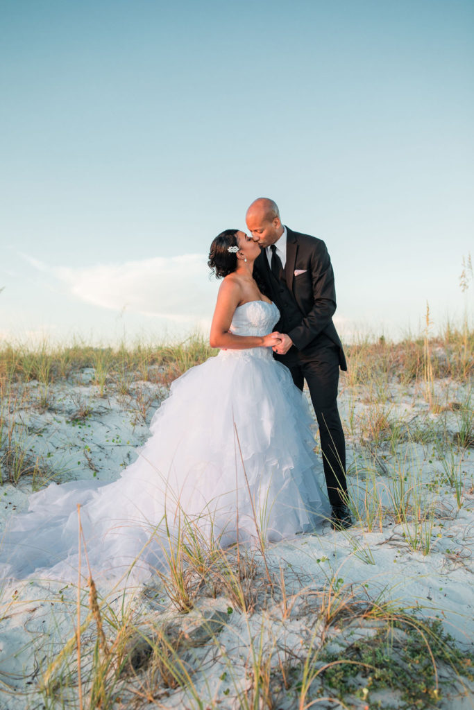 Beach wedding portraits at sunset in the lush grasses of an African-American couple that got married at the Emerald Grande Resort in Destin, Florida