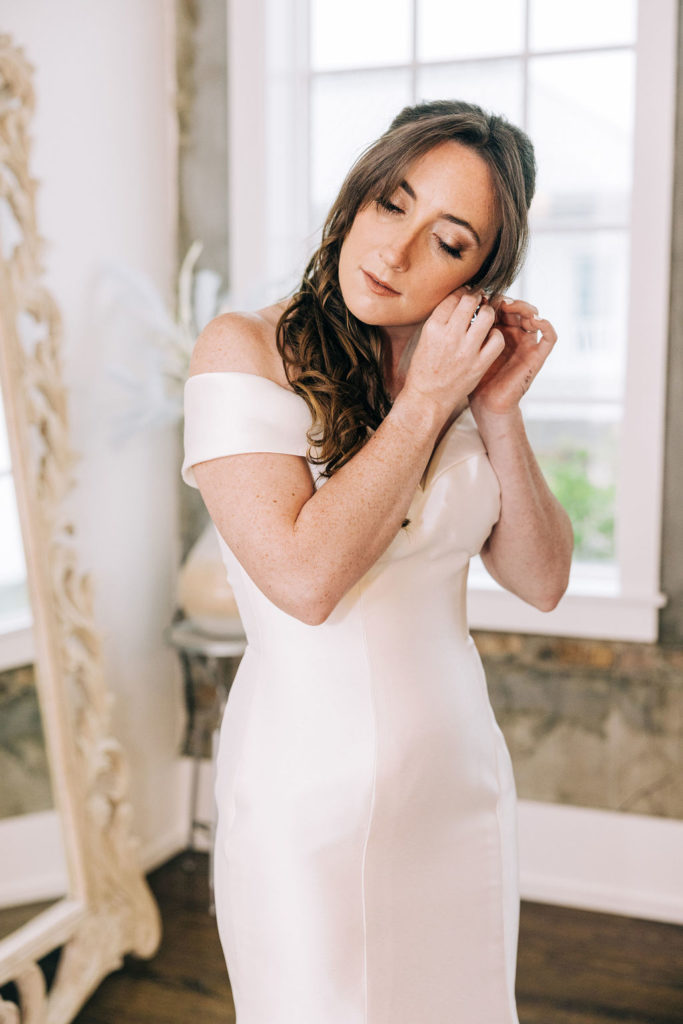5-Eleven Palafox Bridal Suite - Bride posing in front of the mirror putting her earrings on