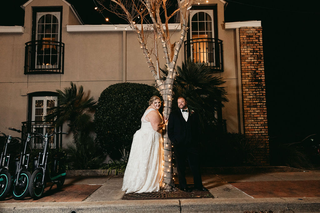 Palafox Wharf Waterfront Wedding event venue bride and groom photos on Palafox during Christmas, with downtown Christmas tree lights