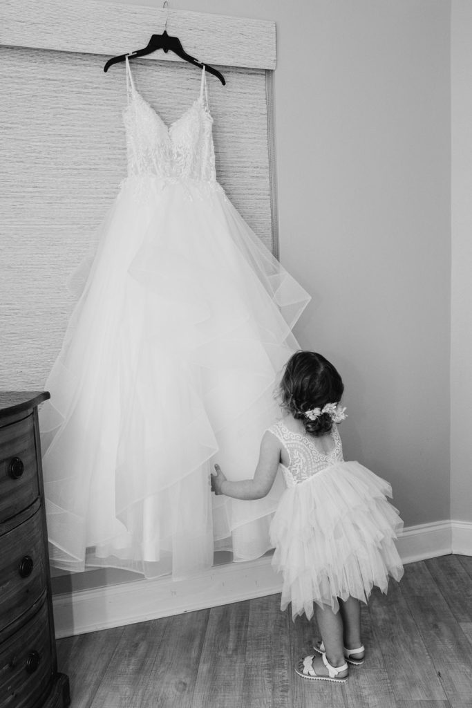 Little girl looking at a bridal dress hanging 