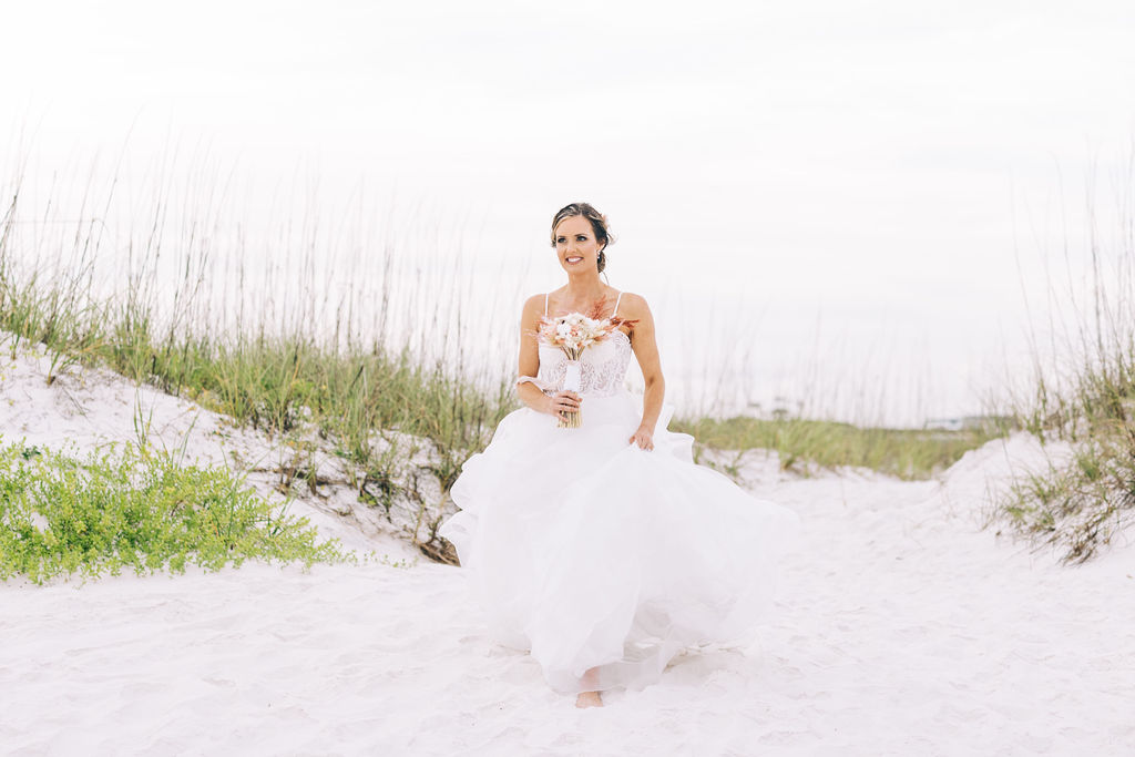 Bride walking on the beach in Pensacola Beach on a cloudy day at sunset before the beach elopement. 