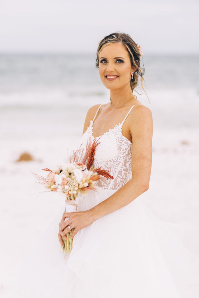 Beautiful bride posing while holding wedding flower bouquet during her photography session in Pensacola Beach.