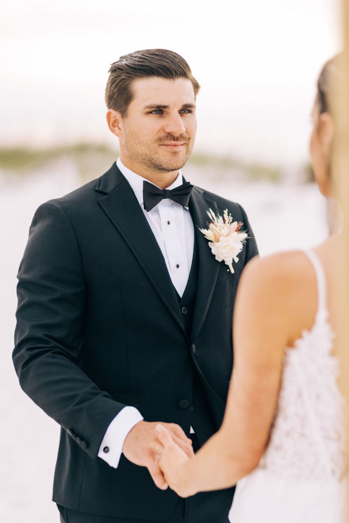 Groom smiling during the ceremony on his elopement day in Pensacola Beach, looking at his bride.