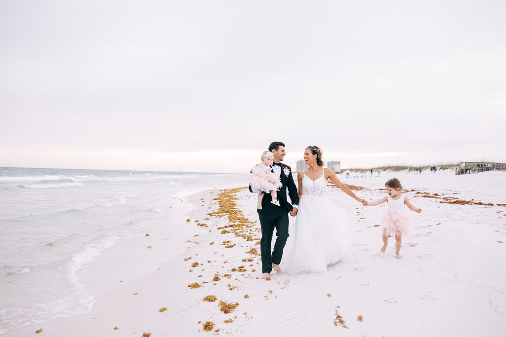 Bride and Groom and their two little girls walking on the beach in Pensacola Beach during their elopement at sunset.