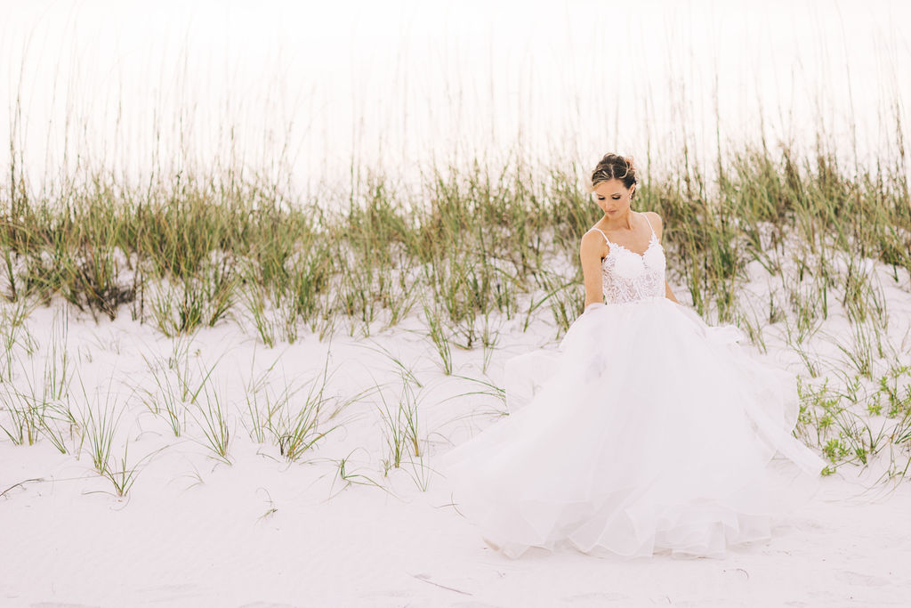 Bride playing with her dress on the beach at sunset
